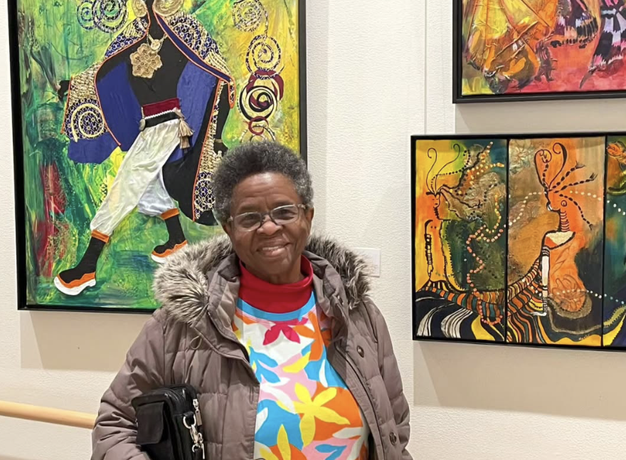 Mary Gill at art gallery with her Caribbean paintings